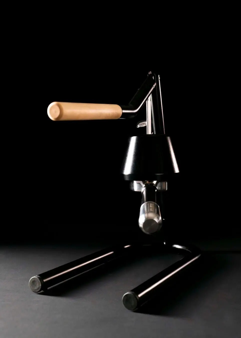 Newton manual espresso maker sitting on black background.